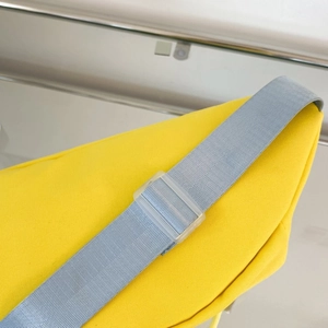Detailaufnahme von grauem Gurt und mattierter Schnalle an einer gelben Segeltuchtasche