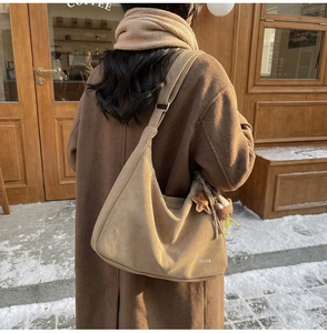 Gros plan d'un sac hobo en daim camel avec des breloques étoile et ours sur le côté