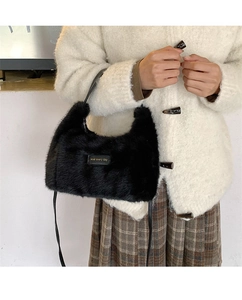 Close-up of black faux fur plush handbag with stitched love every day label and strap