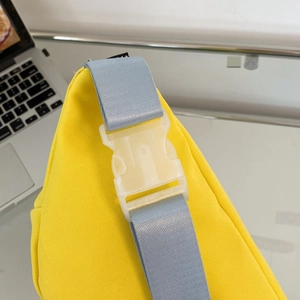 Detail der gelben Canvas-Tasche mit hellblauem Gurt und weißer Steckschnalle