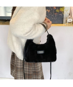 Detail showing the black plush shoulder bag material and golden love every day badge
