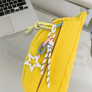 Detailansicht der gelben Canvas-Gürteltasche mit Sternanhänger und bunten Zippern