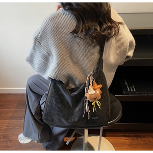 Détail du sac hobo noir en daim avec breloques d'ours et d'étoiles dans un décor intérieur