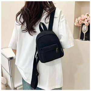 Side view of a black mini nylon backpack worn by a model in a bright modern home setting