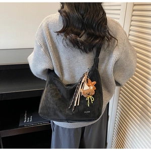 Détail d'un grand sac cabas noir porté par un mannequin dans un salon épuré