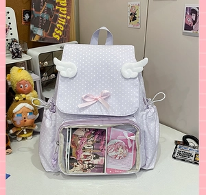 Detail of purple polka dot ita bag with white wings decoration and clear window layer