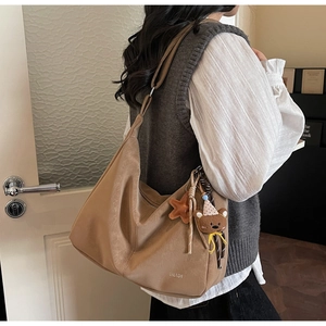Détail du sac cabas kaki avec pendentifs ours et étoile dans un décor intérieur décontracté
