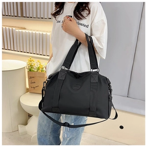 Detail of reinforced handles and adjustable shoulder strap on large black travel bag