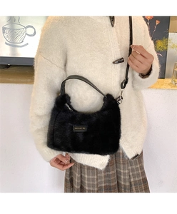 Detail of black faux fur shoulder bag with leather Love Every Day label and soft texture