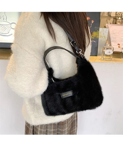 Detail of black faux fur shoulder bag with 'love every day' leather tag on model