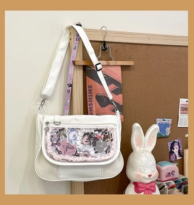Close-up of a white Japanese ita bag with a clear window and pink wave trim for anime badges