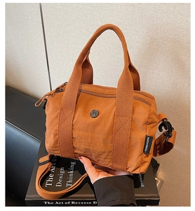 Close-up of caramel nylon fabric texture and woven handle of the crossbody bag