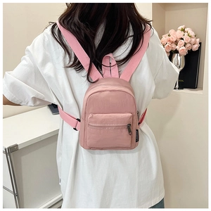 Pink mini nylon backpack with zipper front pocket and brand label detail