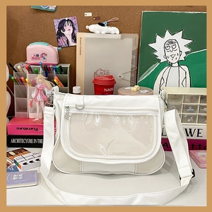 Detail of white messenger bag featuring a transparent display window and butterfly pendant