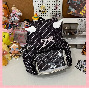 Detail of black polka dot ita bag with plush wings, ribbon bows and clear display window