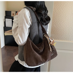 Vue latérale du grand sac cabas en daim marron foncé avec inscription et pendentif