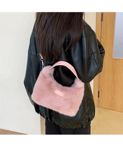 Detail of soft sakura pink faux fur handbag featuring smooth leather handle and plush texture