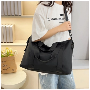 Close-up of black travel tote with durable wide handles and adjustable nylon shoulder strap