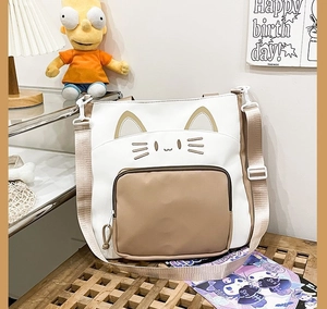 Nahaufnahme der weiß-beigen Canvas-Tasche mit Katzenstickerei und verstellbarem Gurt