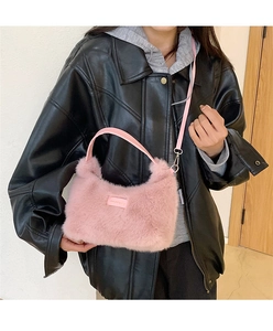 Detail view of pink plush faux fur shoulder bag with leather strap and metal clasp on model