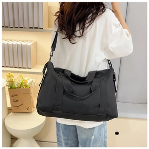Close-up of a large black waterproof travel bag with adjustable strap on female model