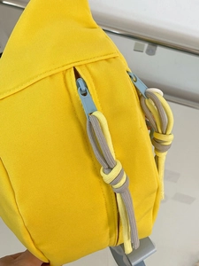 Nahaufnahme der gelben Canvas-Brusttasche mit blauem Reißverschluss und Kordelzug