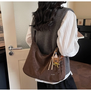Détail du sac hobo vintage marron avec pendentif ours sur l'épaule d'un mannequin