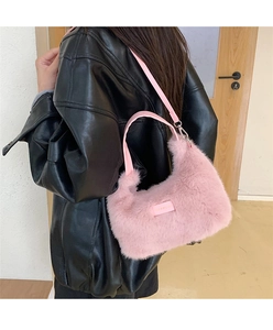 Detailed close-up of a pink faux fur shoulder bag with leather strap on a model