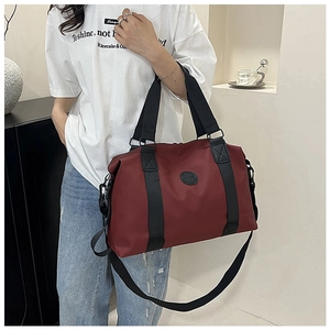 Detailed view of the large capacity burgundy travel duffel bag with black straps and logo