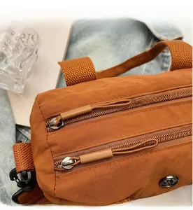 Detail view of the smooth dual zipper closure on a brown casual nylon shoulder bag