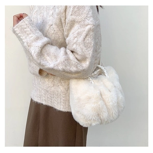 Chic white faux fur shoulder bag with woven handle shown in a warm winter fashion look