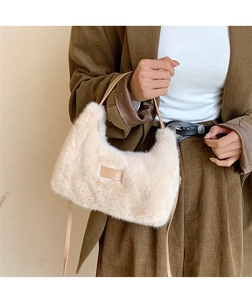 Detailed texture of the soft beige faux fur handbag and its elegant leather brand tag