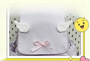 Detail of purple polka dot backpack with plush white wings and pink silk bow