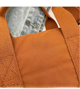 Close-up of brown nylon tote bag featuring metal VM logo buckle and textured strap