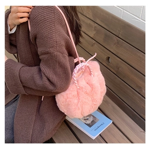 Detail of pink faux fur cloud bag with woven handle shown in lifestyle setting