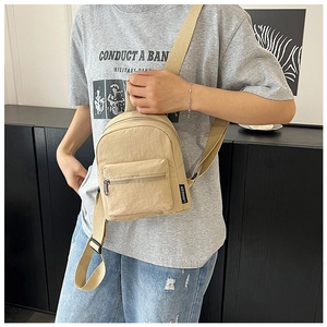 Detail of khaki nylon mini backpack showing the side brand label and durable fabric texture
