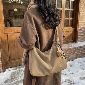 Sac fourre-tout rétro en daim kaki avec logo et breloque ours dans un décor d'hiver