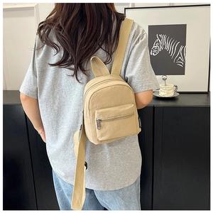 Close-up of khaki mini nylon backpack with metal zippers and woven shoulder straps