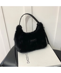 Close-up of black plush handbag with 'love every day' tag and leather shoulder straps