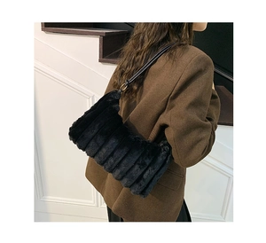 Close-up of black plush faux fur shoulder bag with leather strap on a model