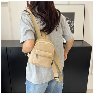 Back view of model wearing a beige mini nylon backpack showing size and adjustable straps