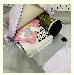 Macro view showing spacious interior of purple polka dot backpack with school supplies