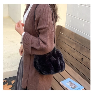 Detail shot of black faux fur cloud bag with a metal chain strap on a model