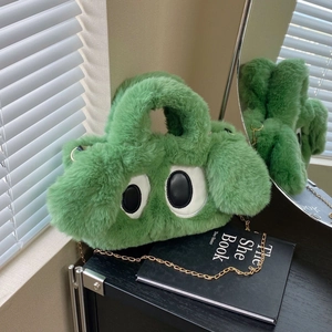 Détail du sac à main en peluche verte avec de grands yeux et une chaîne dorée
