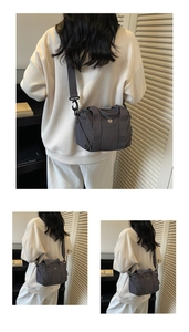 Detailed view of a dark grey nylon crossbody bag with adjustable wide fabric shoulder strap