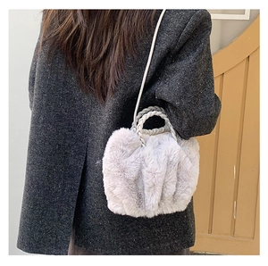 Detail of plush faux fur cloud bag featuring woven handles and crossbody strap