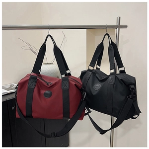 Detail of burgundy and black travel bags with reinforced handles and durable fabric texture