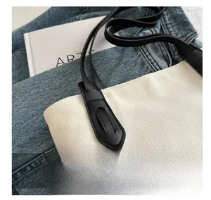 Gros plan du sac en toile montrant les détails de couture et la bandoulière en cuir