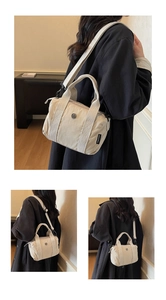 Detailed close-up of cream nylon canvas tote bag featuring metal buckle and woven side label