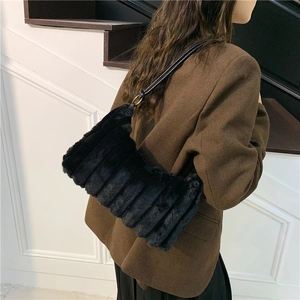 Detail of plush black faux fur handbag featuring vertical stripes and gold metal hardware